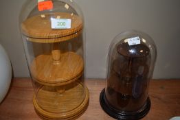 Two wooden tiered display stands with glass dome covers.