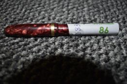 A gold tipped Conwy Stewart fountain pen having red marble effect body.