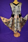 A vintage 1950s gold dress with flocked pattern and black velvet detailing to neckline and skirt,