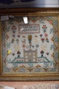 A framed cross stitch sampler by Annie Akister, aged 11 1885, depicting a castle, animals and floral