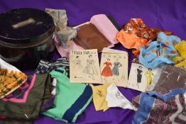 A metal sailors hat tin containing an assortment of 50s dress patterns, stockings,scarves and