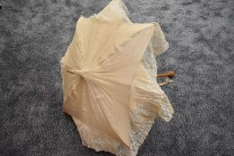 An early 20th century cream slub silk parasol with an abundance of tulle lace surrounding the