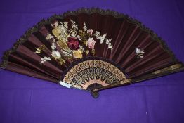 A late 19th/early 20th century maroon silk fan, satin leaf embroidered with basket of flowers and