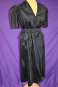 A vintage 1940s black dress with peplum waist, covered buttons to front and belt to waist,larger