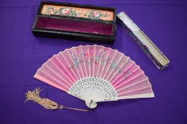 A pink gauze fan in case,having floral embroidery and tassel to carved handle, also included is