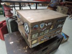 A pine box decorated with numerous car badges.