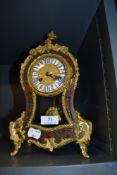A French style balloon clock having extensive brass detailing and visible pendulum with enamel