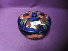 A Moorcroft lidded bowl having Anemone pattern on blue ground.