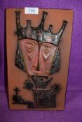 A terracotta wall plaque having tribal style decoration.