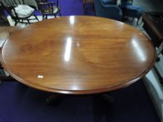 A Victorian mahogany fold over dining table of oval form on pedestal base, with quadruple scroll