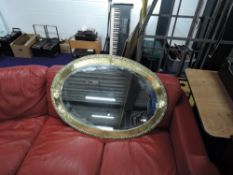 A large Arts and Crafts style brass oval wall mirror, width approx. 100cm