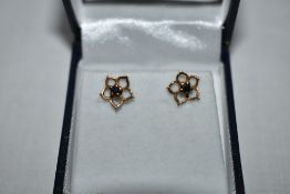 A pair of 9ct gold stud earrings having sapphire chips in open petal surrounds, approx 1g