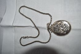 An HM silver locket having engraved scroll decoration on a snake link chain