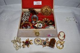 A small vintage jewellery box containing a selection of costume jewellery brooches