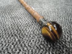A bamboo shafted walking cane having HM silver ferrule holding Tigers eye stone globe handle