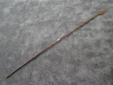 A tribal spear having solid wood shaft with wrought iron head and guards measuring 180cm long