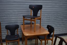 A vintage teak or sapele dining table and four similar chairs of stylised form having PVC seats