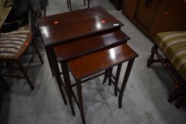 An early 20th Century mahogany and line inlaid nest of three tables on shaped legs, width of largest