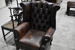 A traditional brown leather wing back armchair
