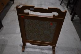 A golden oak firescreen having woolwork inset, width approx. 47cm