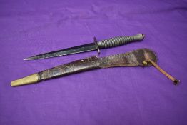 A Fairburn Sykes Commando Knife, 3rd Pattern, with leather and brass scabbard, overall length appro