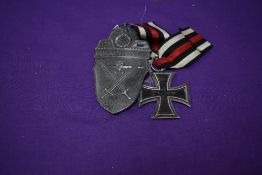 A German WW1 Iron Cross dated 1813-1914 and a German WW2 Demjansk 1942 Shield, bearing cross