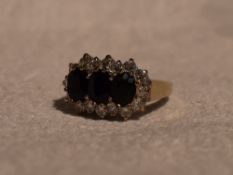 A lady's dress ring having a trio of sapphires within a cubic zirconia border in a stepped claw