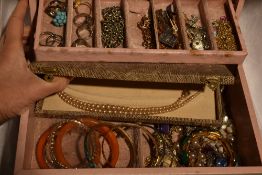 A pink jewellery box containing a selection of costume jewellery including rolled gold bracelet,