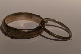An HM silver hinged bangle having floral and scroll decoration and a child's similar bangle