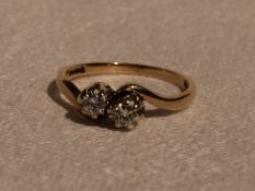 A lady's dress ring having two diamonds, each approx 0.1ct in claw set mounts to crossover shoulders