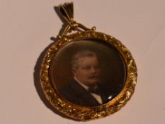 A yellow metal glass locket containing hand painted Edwardian portraits within a decorative