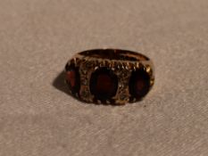 A lady's dress ring having three oval garnets interspersed by six cubic zirconia in a gallery