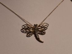 A 9ct white and yellow gold pendant modelled as a dragonfly on a 9ct gold fine link chain, approx