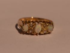 A lady's dress ring having three graduated opals interspersed by diamond chips in a gallery mount on