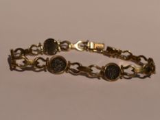 A yellow metal articulated bracelet stamped 14 having five inset panels bearing lettering possibly
