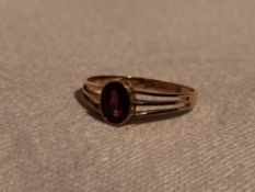 A lady's dress ring having an oval ruby style stone in a collared mount to open triple bar shoulders