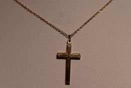 A yellow metal cross stamped 10K having engraved line decoration on a yellow metal chain, approx 2.