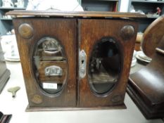 A miniature oak cased jewellery box with internal drawers and beveled glass doors