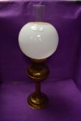 A brass table top oil lamp with spherical milk shade.