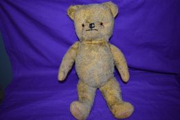 A mid 20th century yellow plush straw filled teddy bear having plastic eyes, stitched nose and