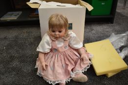A modern Celia Doll Company bisque headed doll having fixed open eyes, clothed and boxed