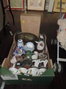 A box containing mugs, vintage cups and saucers and vases, brass tray and more.