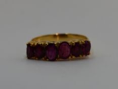 A lady's dress ring having six graduated oval rubies in a claw set gallery mount on a yellow metal
