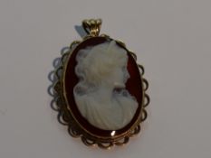 A carved agate cameo brooch/pendant depicting a maiden in profile on an orange agate ground in a 9ct