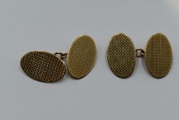 A pair of 9ct gold cufflinks of oval form having engine turned chequered decoration and chain