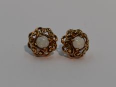 A pair of 9ct gold stud earrings having central opal cabouchons in a shaped pierced mount