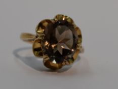 A lady's dress ring having an oval smoky quartz in an open frilled claw set mount on a 9ct gold