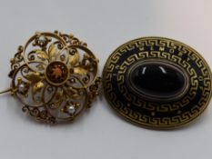 A yellow metal brooch having central coral pearl within an open foliate and scroll mount having seed