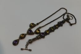 An amethyst and citrine necklace having five stones in decorative silver mounts on a fixed snake