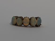 A lady's dress ring having five oval opal cabouchons of even form in a claw set mount on a yellow